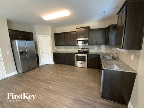 A kitchen with a refrigerator, microwave, oven, and sink.
