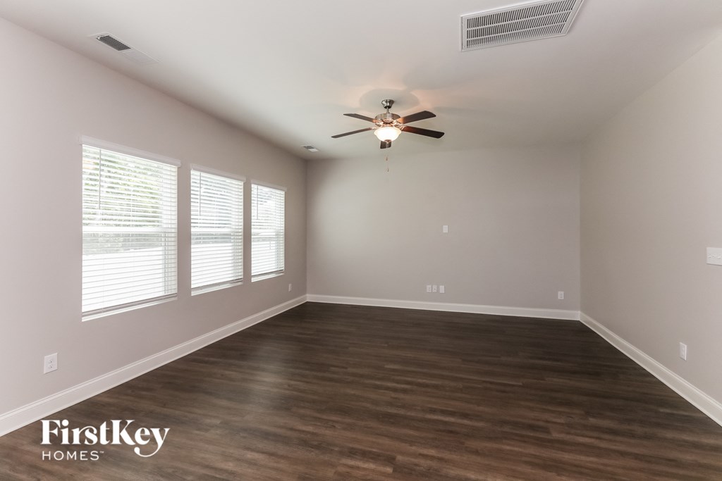 an empty living room with wood floors and a ceiling fan