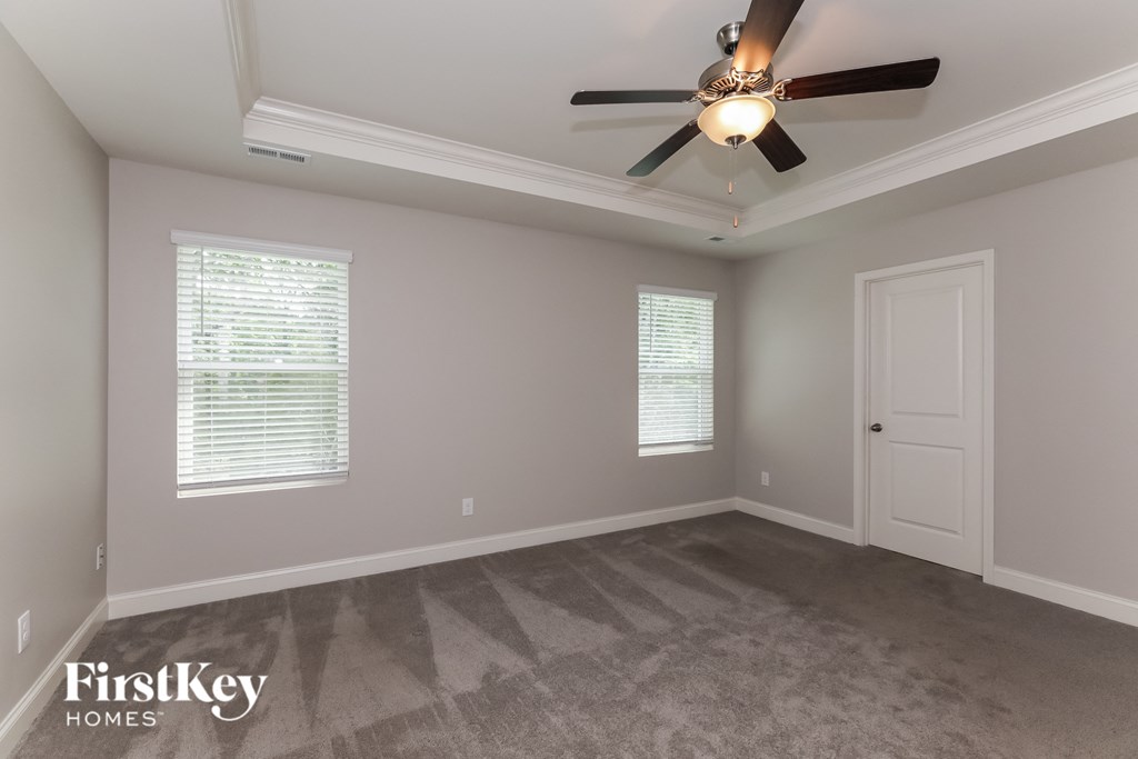 an empty living room with a ceiling fan and a door