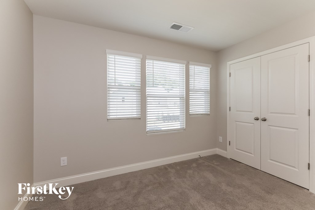 a bedroom with a carpeted floor and white doors and windows