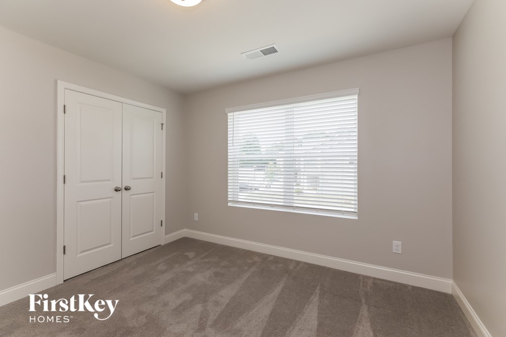 a bedroom with a door and a window and a carpeted floor