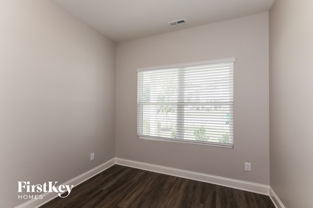 a bedroom with a large window and wooden floors