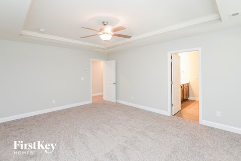 a spacious living room with carpet and a ceiling fan