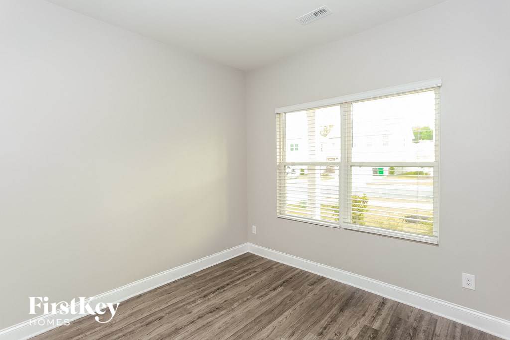 a bedroom with a large window and wooden floors