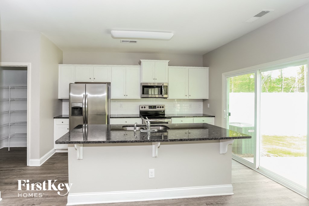 a kitchen with white cabinets and a black counter top