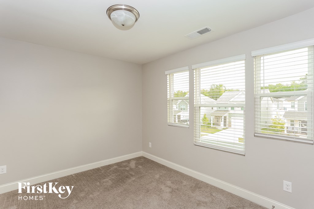 a bedroom with three windows and a carpeted floor