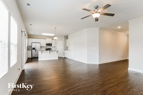 A spacious kitchen and living room with wooden floors and white walls.