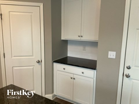 A kitchen with white cabinets and a black countertop.