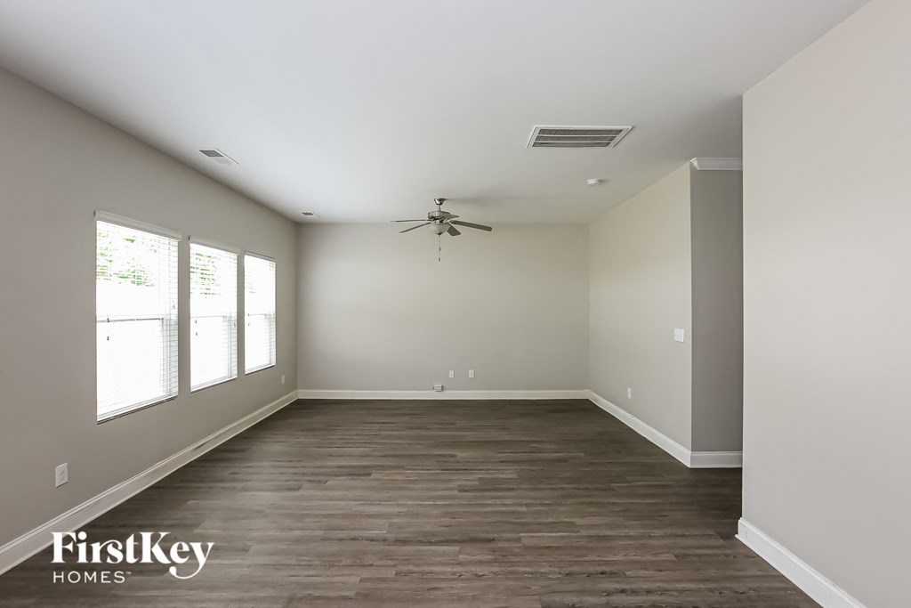 a clean empty living room with wood floors and a ceiling fan
