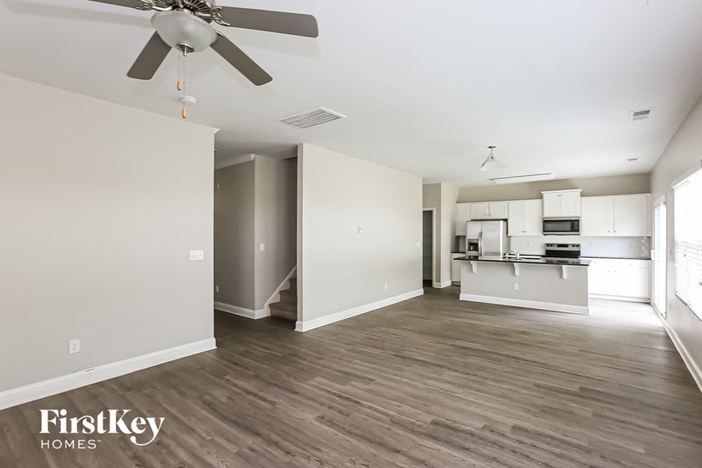 a renovated living room and kitchen with white walls and wood flooring