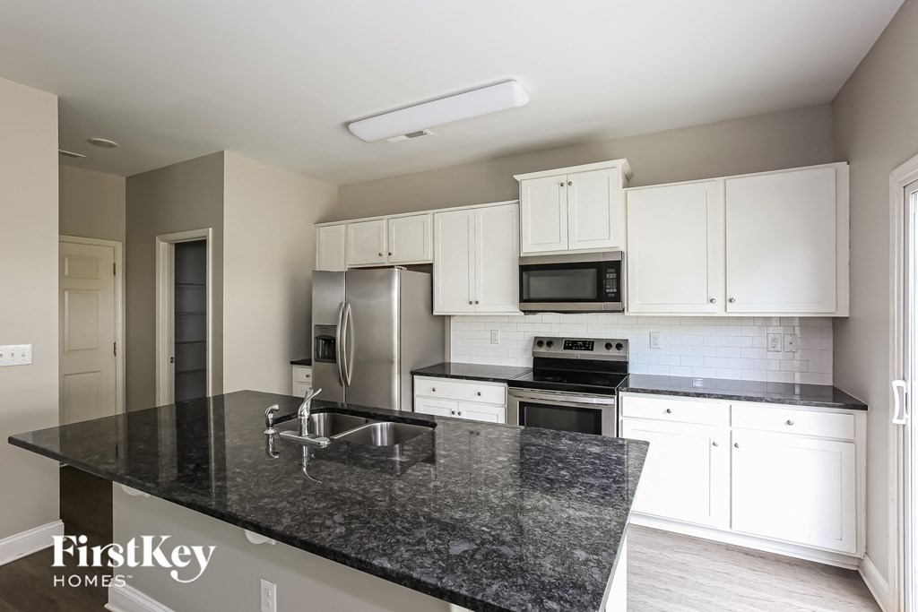 a kitchen with white cabinets and granite counter tops