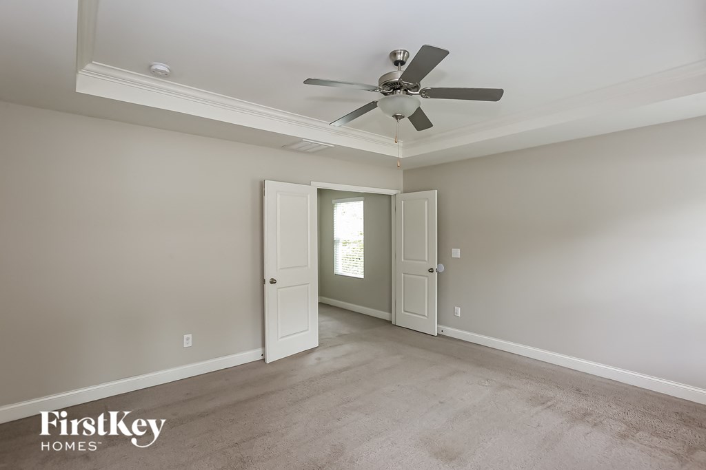 a empty living room with a ceiling fan and a door