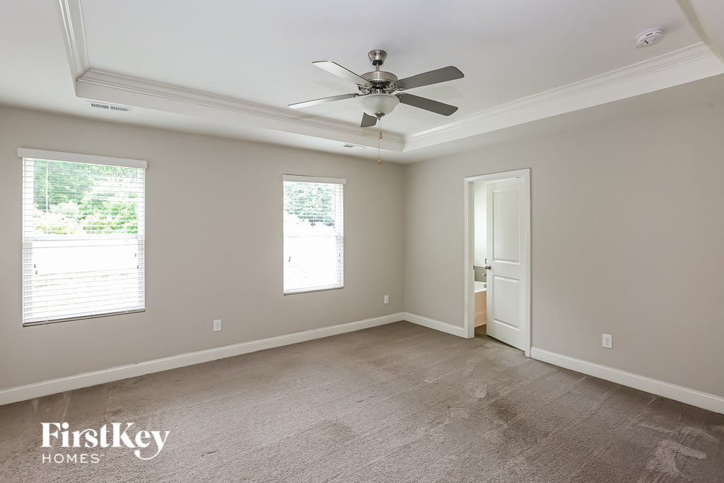 a empty living room with a ceiling fan and a door