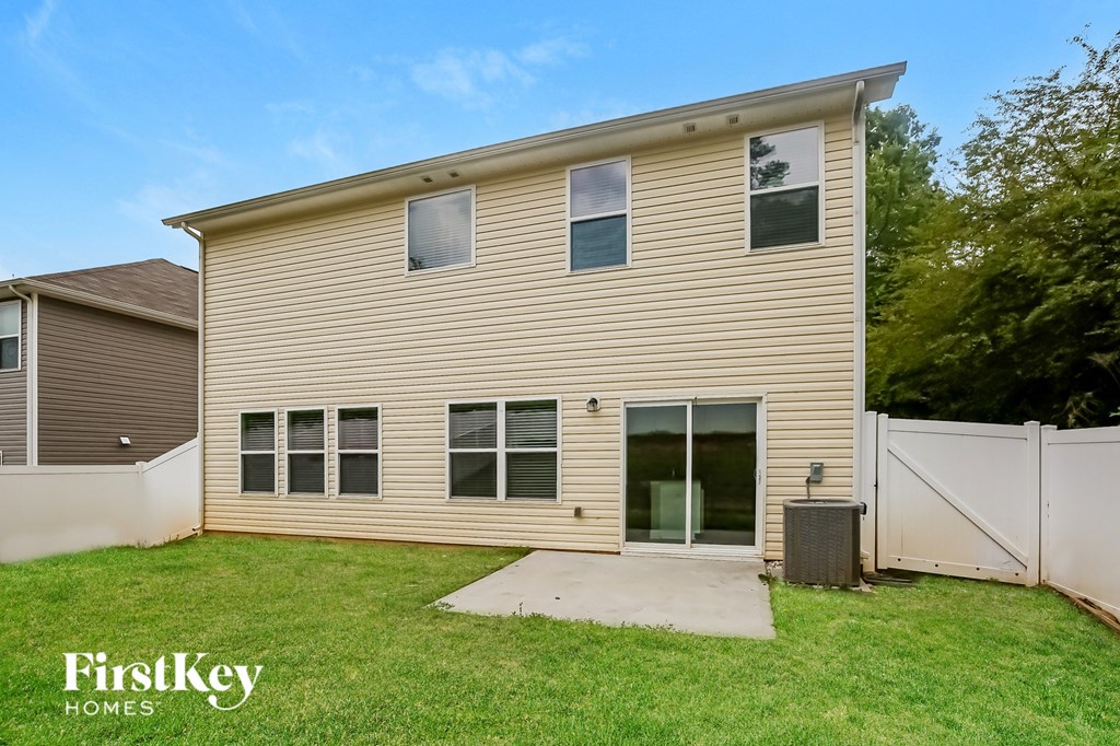 the back of a house with a yard and a white fence