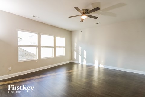 A spacious room with a ceiling fan and wooden flooring.