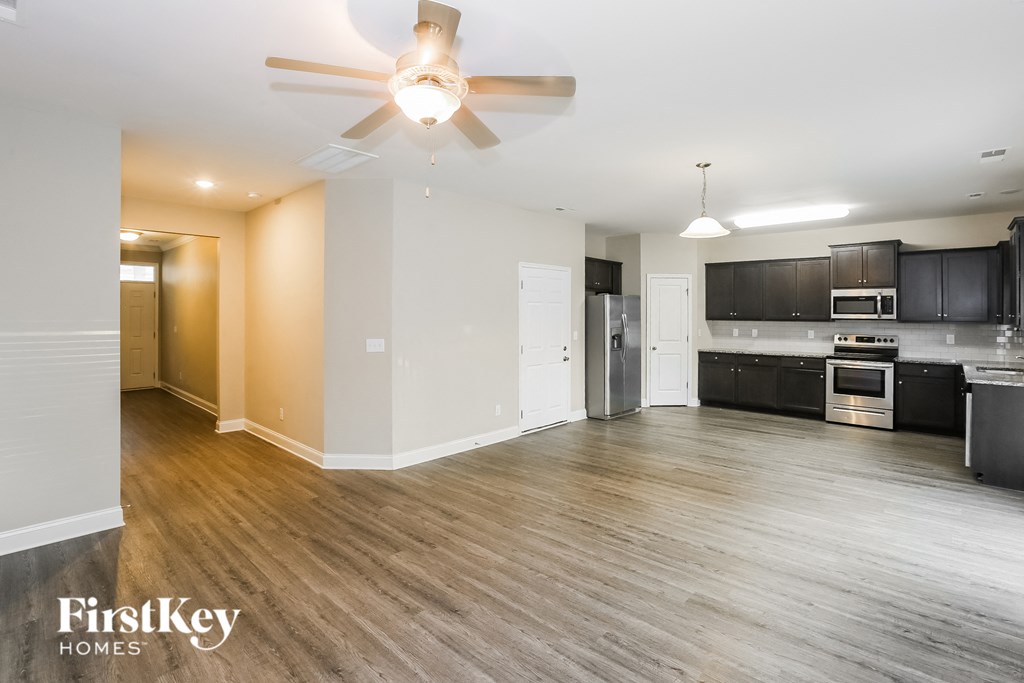 A spacious kitchen and living room with wooden floors and modern appliances.