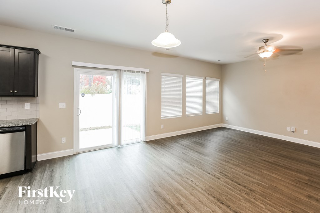 A spacious room with wooden flooring and a kitchen area with a stainless steel dishwasher.