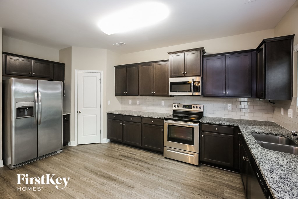 A kitchen with a refrigerator, oven, microwave, and cabinets.