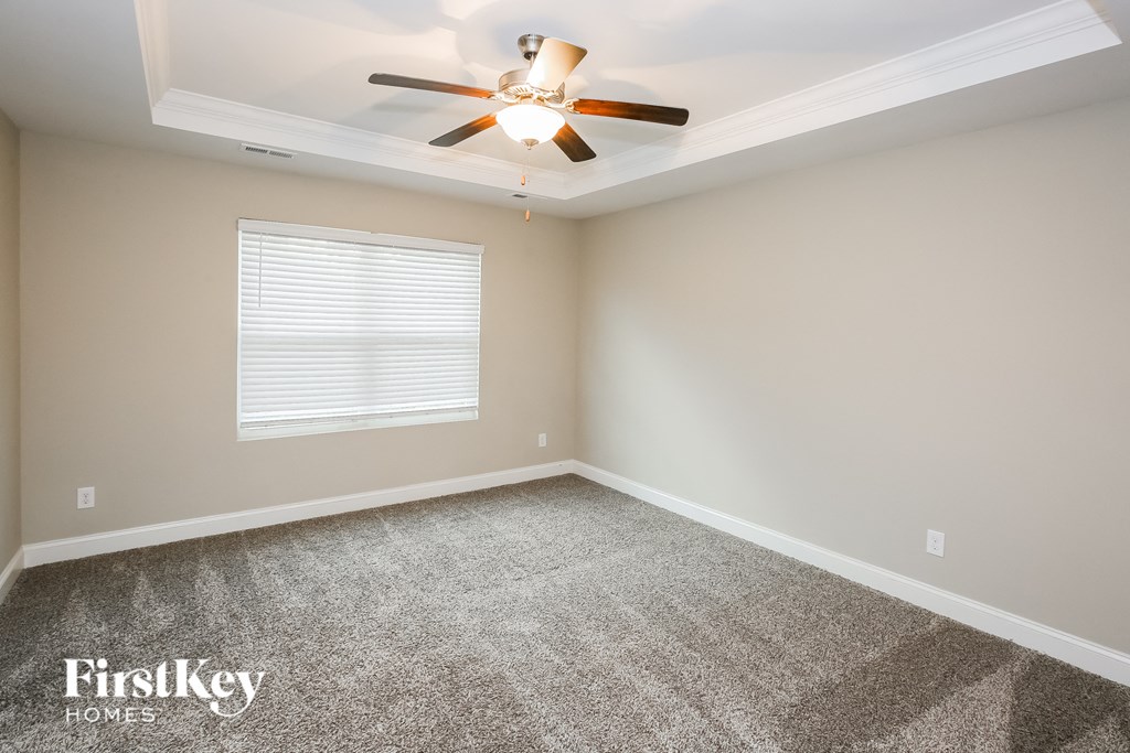 A room with a ceiling fan and a window with blinds.