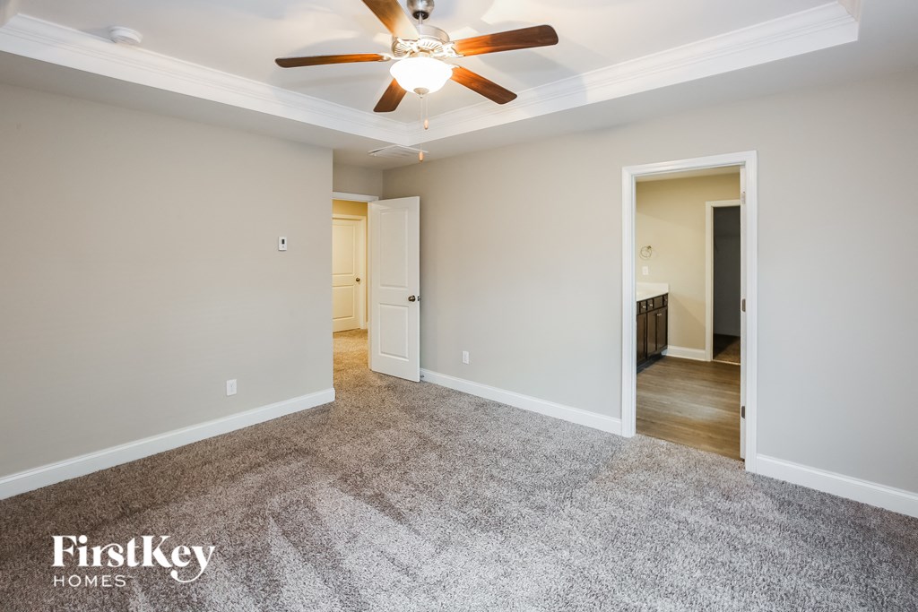 A spacious room with a ceiling fan and carpeted floor.