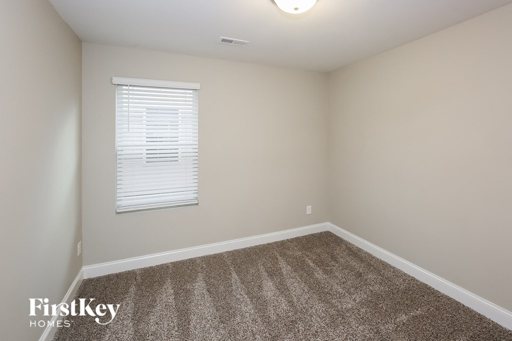 A room with a carpeted floor and a window with blinds.