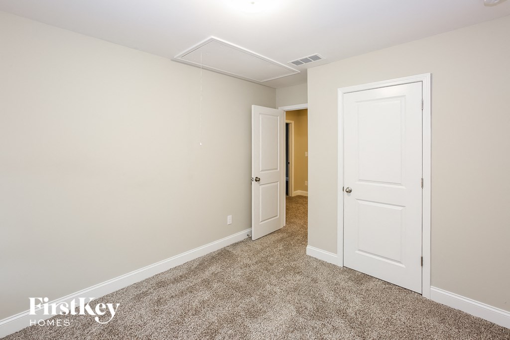 A room with a carpeted floor and two doors.