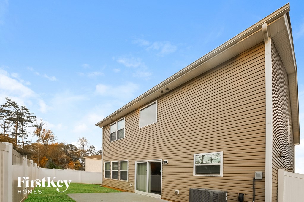 A modern house with a brown siding and a white fence.