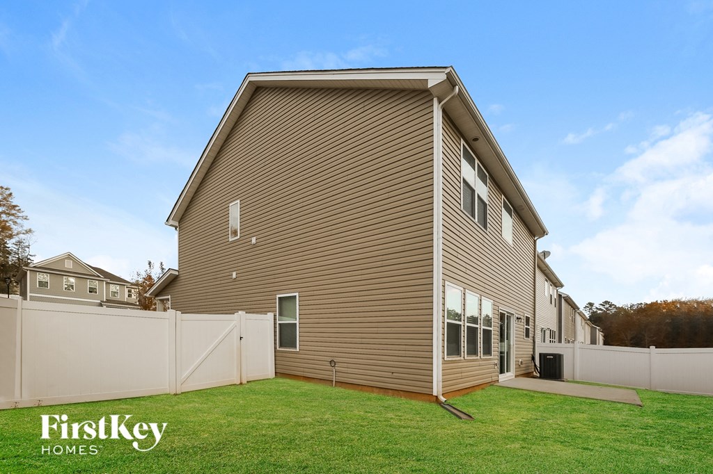 A house with a brown siding and a white fence is for sale by FirstKey Homes.