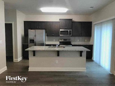 A kitchen with a refrigerator, microwave, oven, and a countertop.