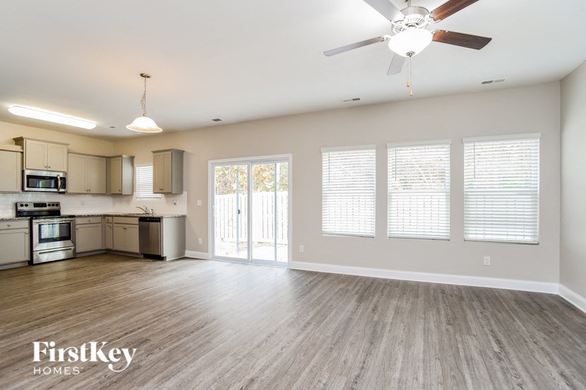 A spacious kitchen and living room with a ceiling fan and lighting fixtures.