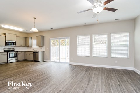 A spacious kitchen and living room with a ceiling fan and lighting fixtures.