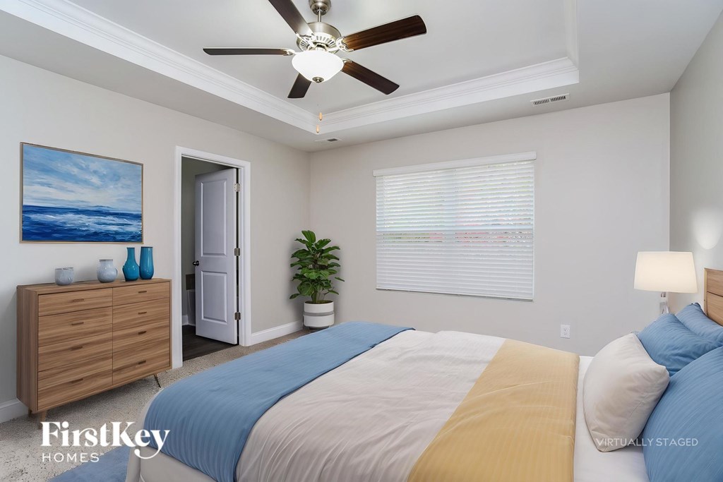A bedroom with a bed, dresser, and a ceiling fan.