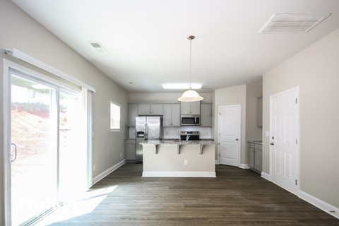 A kitchen with white cabinets and a wooden floor.