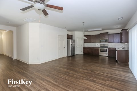 A spacious kitchen with dark brown cabinets and a white ceiling fan.