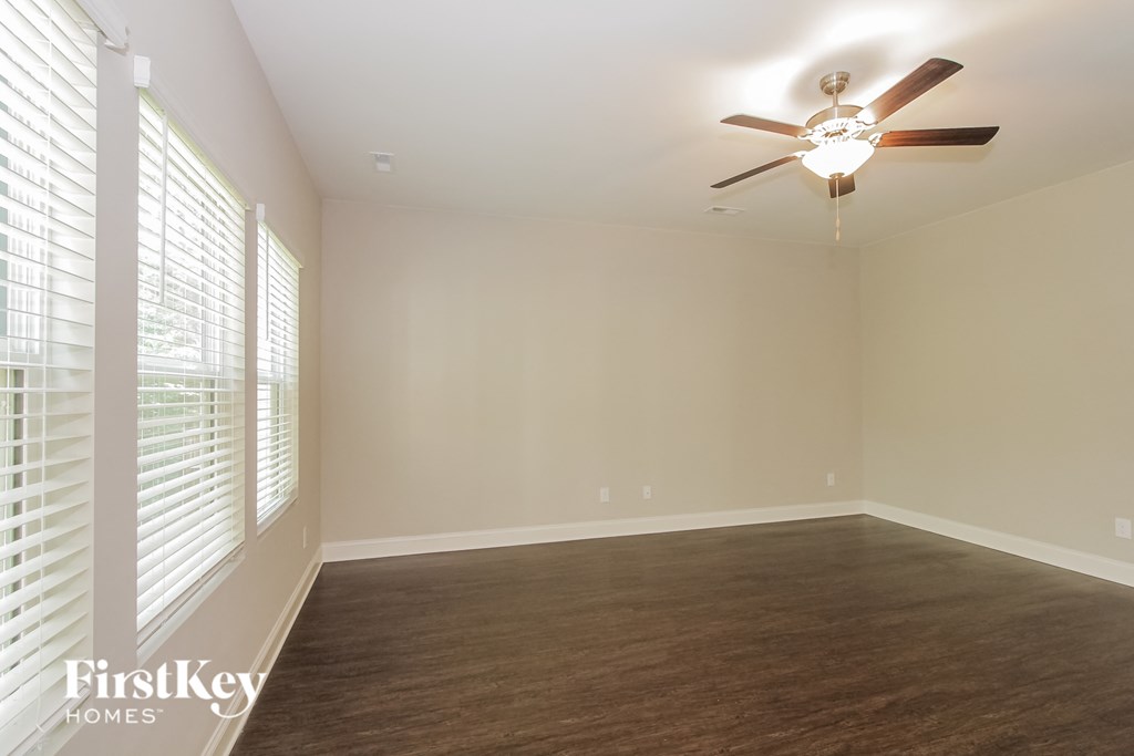 an empty living room with a ceiling fan and a large window