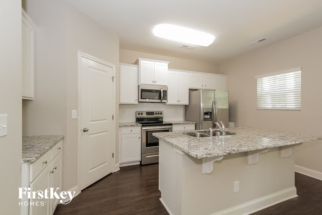 a kitchen with white cabinets and granite counter tops and a sink