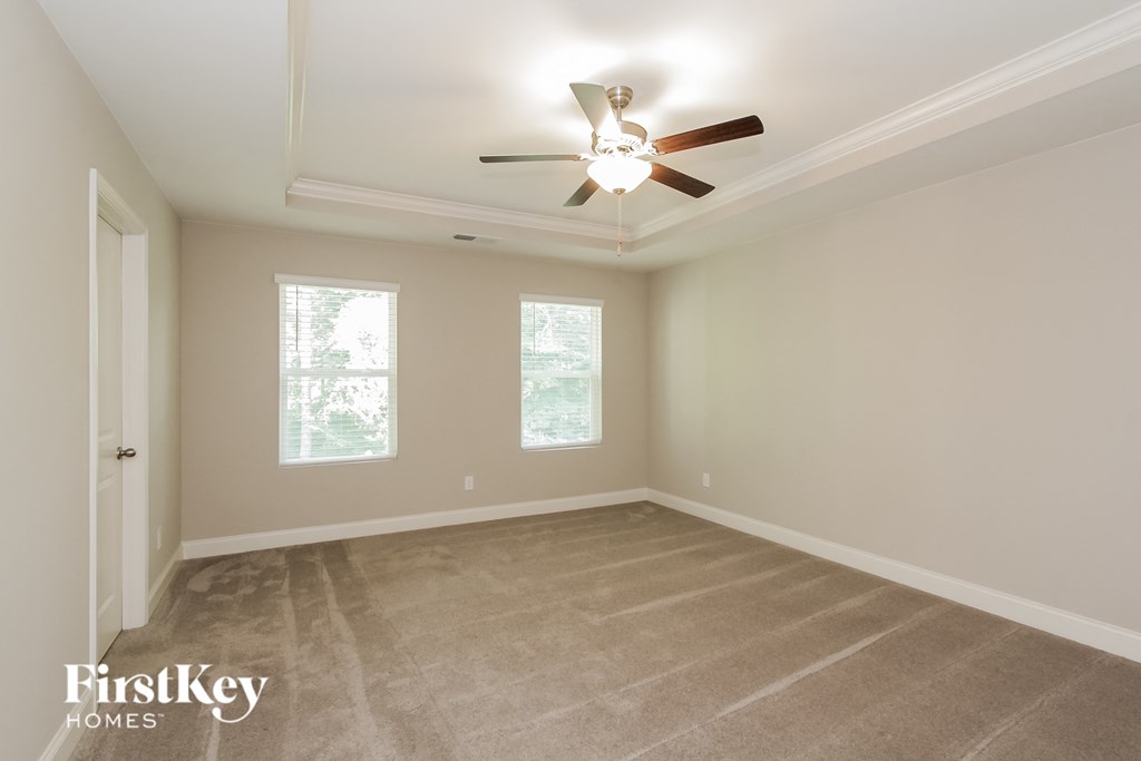 an empty room with a ceiling fan and two windows