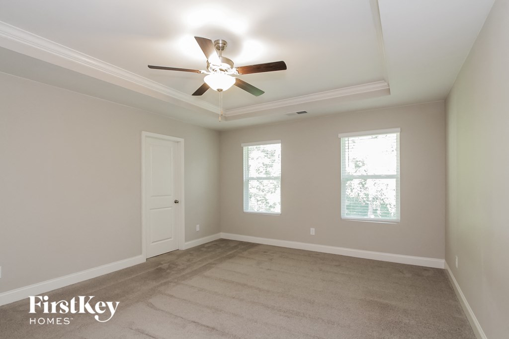 an empty room with a ceiling fan and two windows