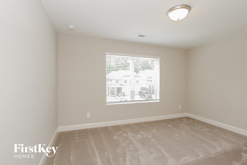 a bedroom with a large window and a carpeted floor
