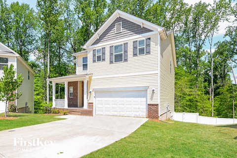 A two-story house with a garage is surrounded by trees.