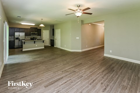 A spacious room with wood flooring and a ceiling fan.