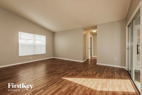 an empty living room with wood flooring and a window