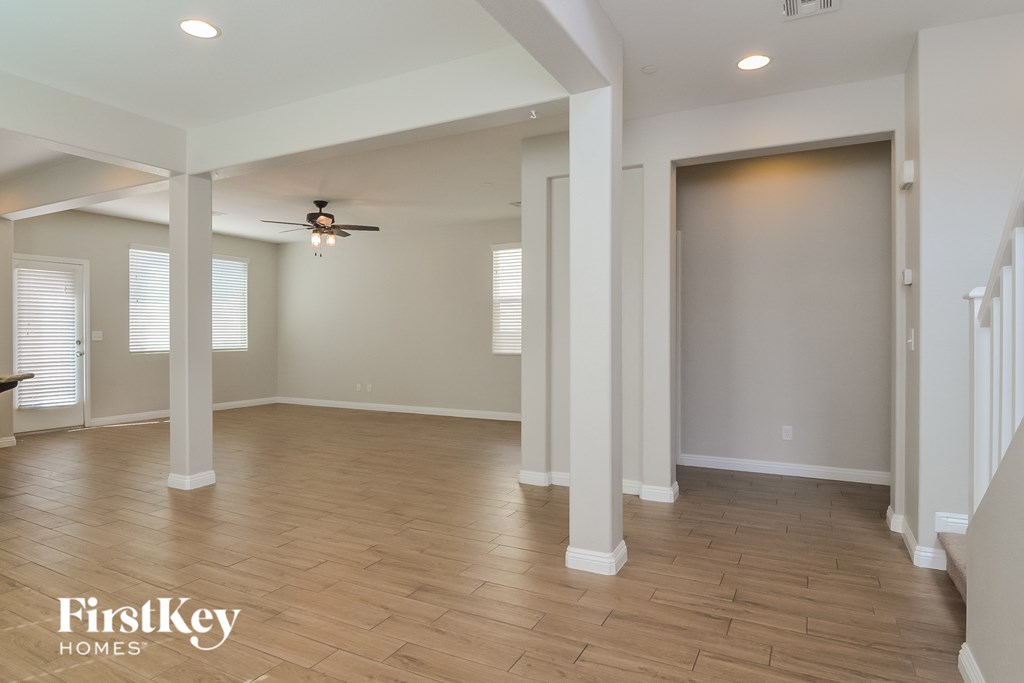 A spacious room with wooden flooring and a ceiling fan.