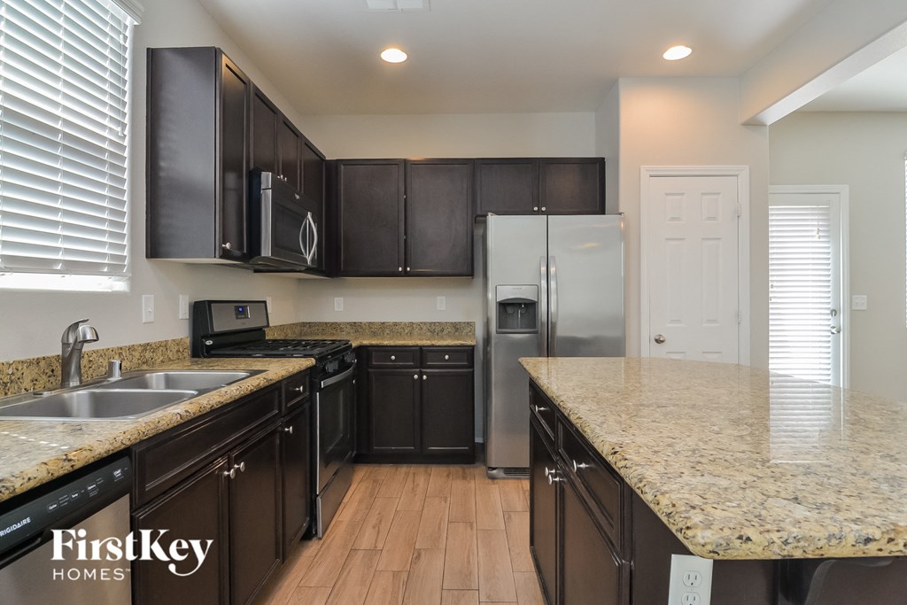 A kitchen with dark brown cabinets and a granite countertop.