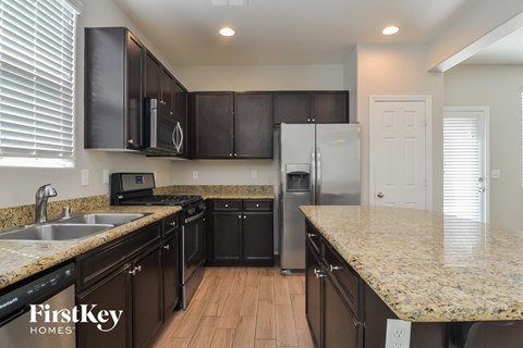 A kitchen with dark brown cabinets and a granite countertop.