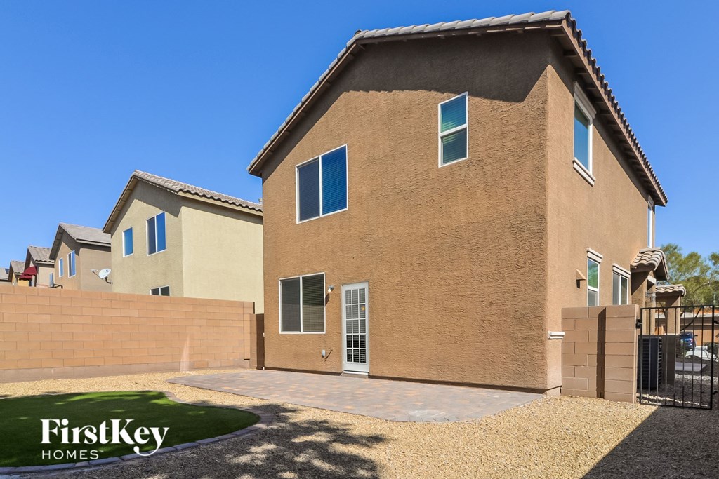 A house with a brown stucco exterior and a black gate in front.