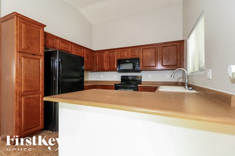 a kitchen with wooden cabinets and a black refrigerator