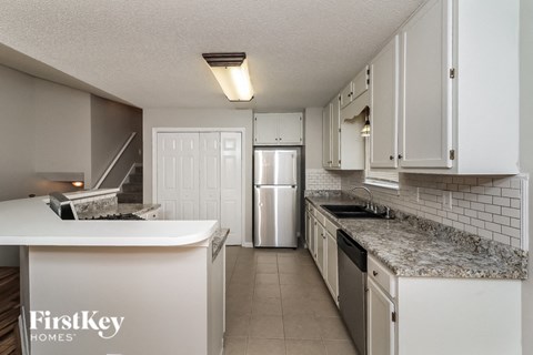 a kitchen with white cabinets and granite counter tops and a white refrigerator