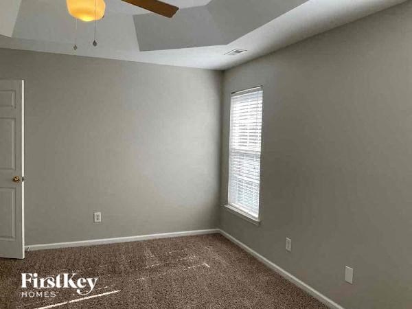 an empty gray room with a window and a ceiling fan