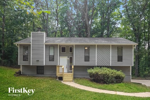 A house with a porch and a chimney is surrounded by trees.